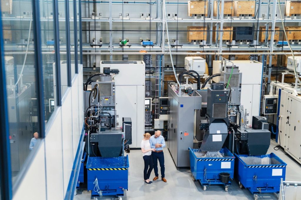 Two professionals standing near machinery in a factory setting