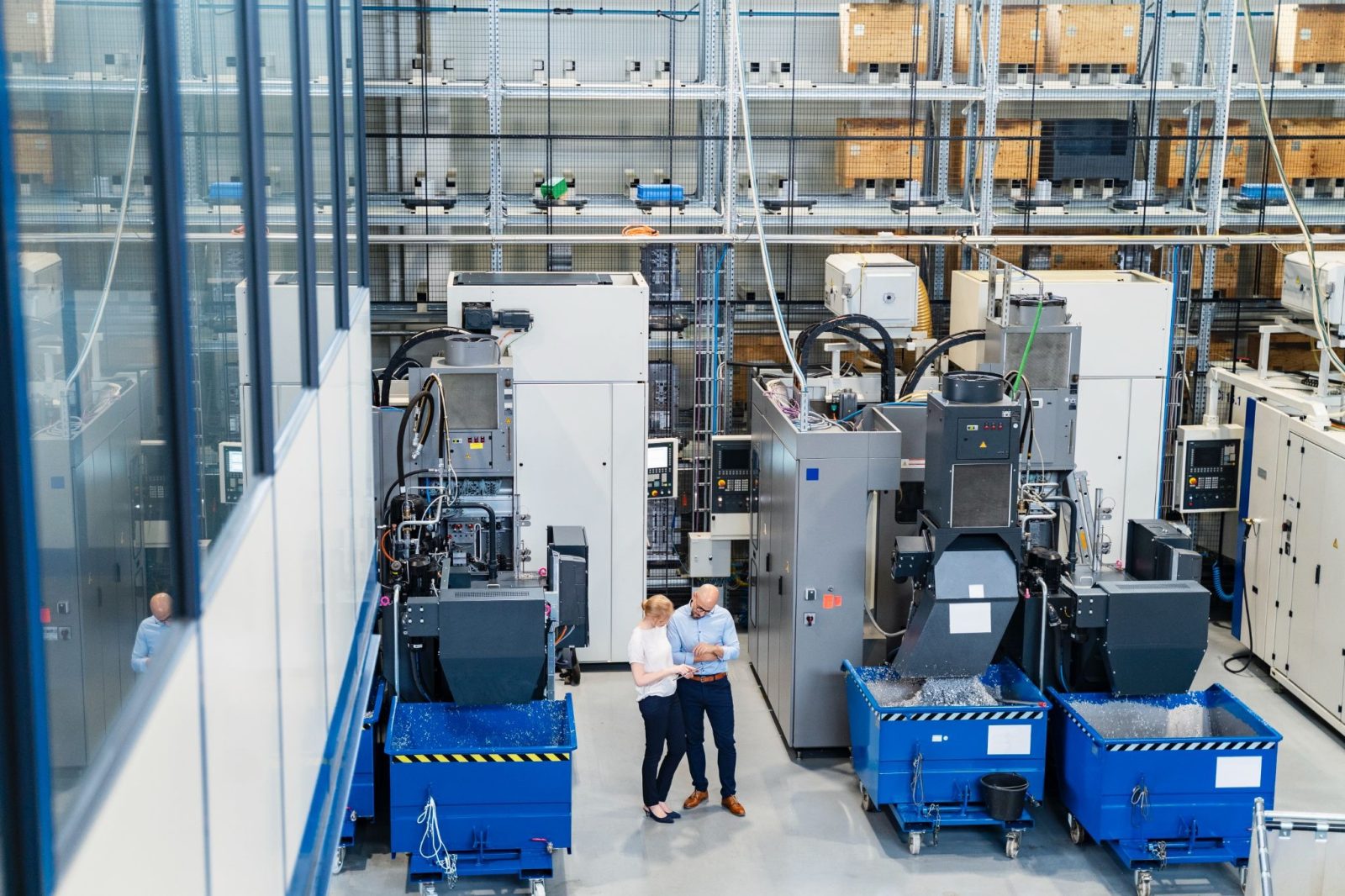 Two professionals standing near machinery in a factory setting