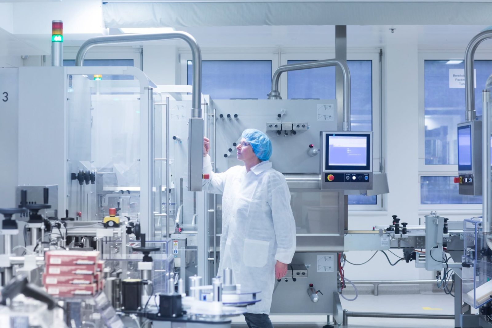 Technician in white lab coat working in a modern pharmaceutical manufacturing plant